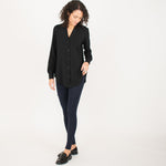 Woman wearing black long sleeve button up shirt with navy fitted leggings