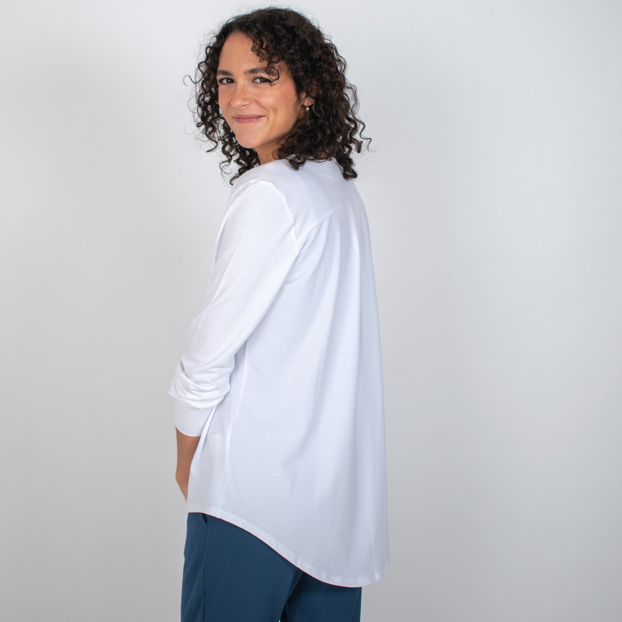 Woman wearing white long sleeve button up shirt with blue pants