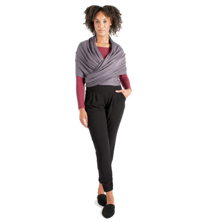 Woman wearing light grey wrap-up scarf around their upper body tied in the back with maroon long sleeve shirt and black pants