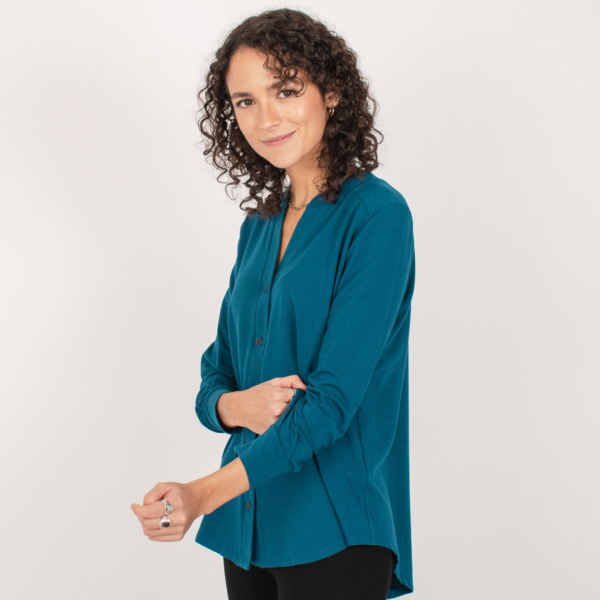 Woman wearing teal long sleeve button up shirt with black fitted leggings
