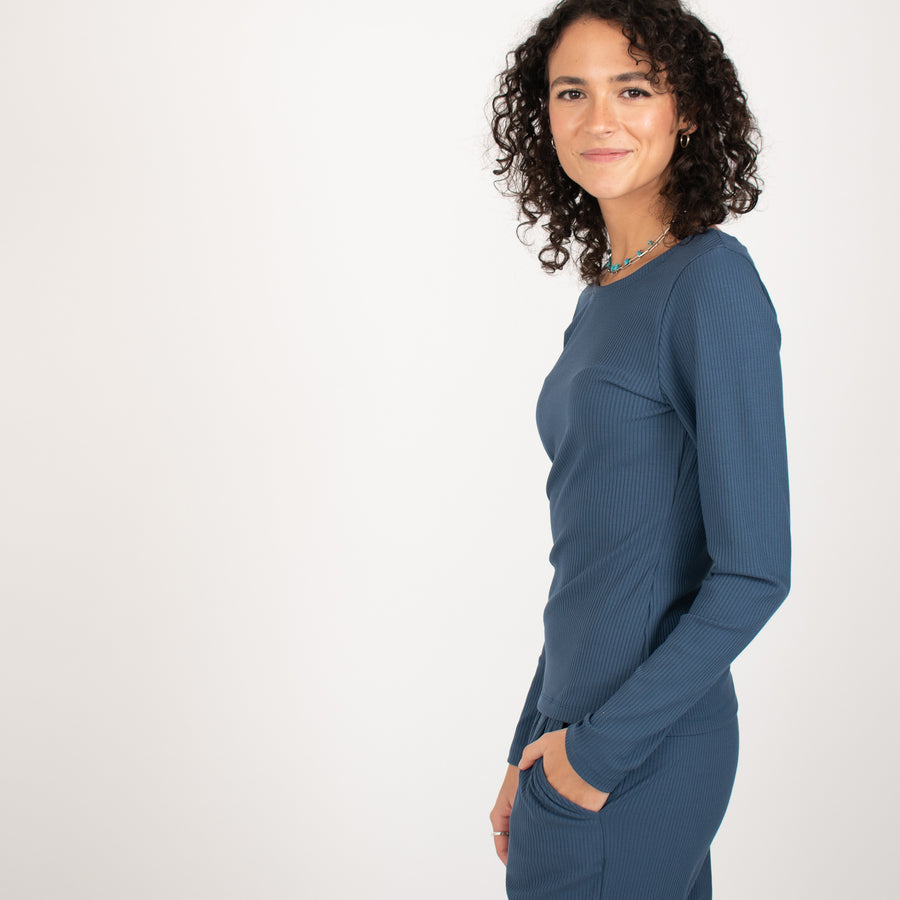 Woman wearing blue rib knit reversible long sleeve top with matching blue fitted sweatpants 