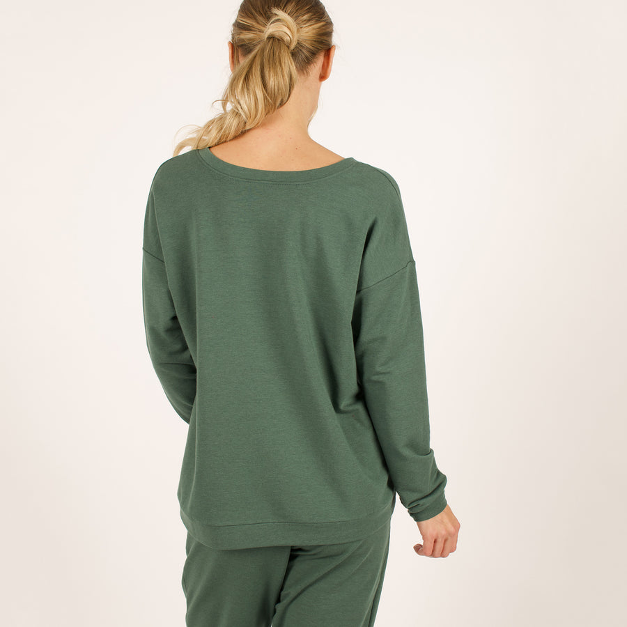 Woman wearing reversible green v-neckline loose sweatshirt with matching green sweatpants
