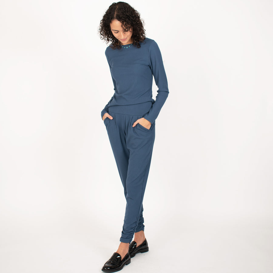 Woman wearing blue rib knit reversible long sleeve top with matching blue fitted sweatpants 