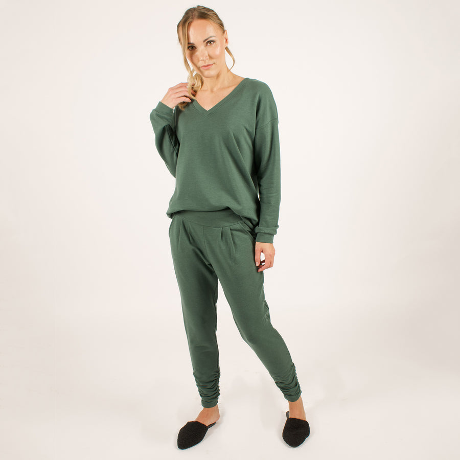 Woman wearing reversible green v-neckline loose sweatshirt with matching green sweatpants