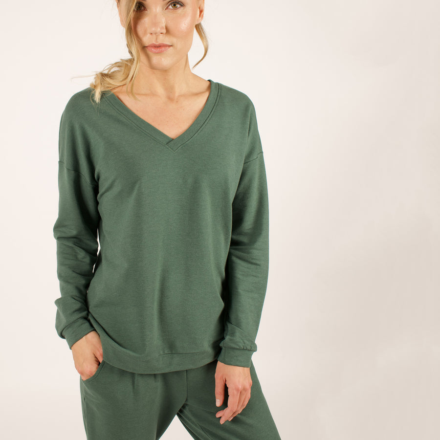 Woman wearing reversible green v-neckline loose sweatshirt with matching green sweatpants
