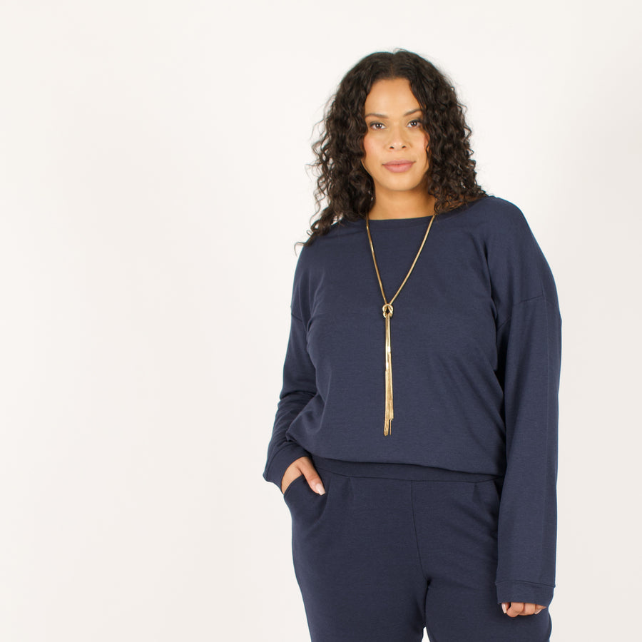 Woman wearing reversible navy blue v-neckline loose sweatshirt with matching navy blue sweatpants