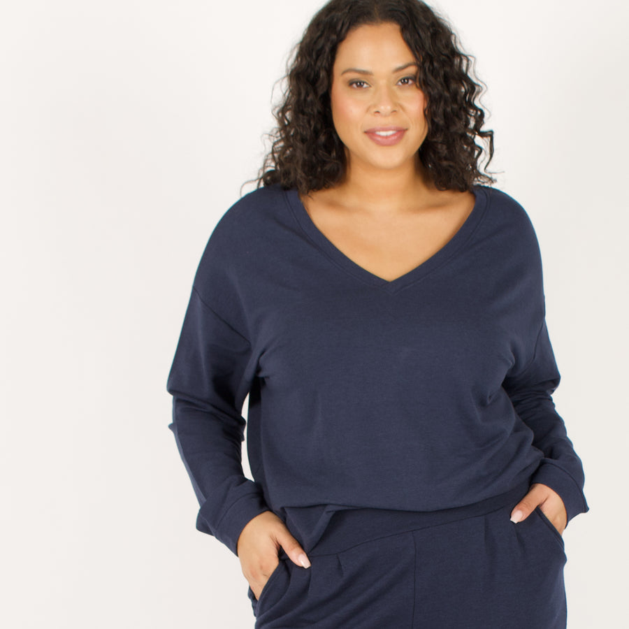 Woman wearing reversible navy blue v-neckline loose sweatshirt with matching navy blue sweatpants