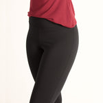 Woman wearing fitted black high-rise waist with ankle length leggings featuring seamless stitching and a hidden back pocket with red shirt