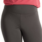 Woman wearing fitted black high-rise waist with ankle length leggings featuring seamless stitching and a hidden back pocket with red shirt