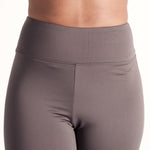 Woman wearing fitted light brown high-rise waist with ankle length leggings featuring seamless stitching and a hidden back pocket 