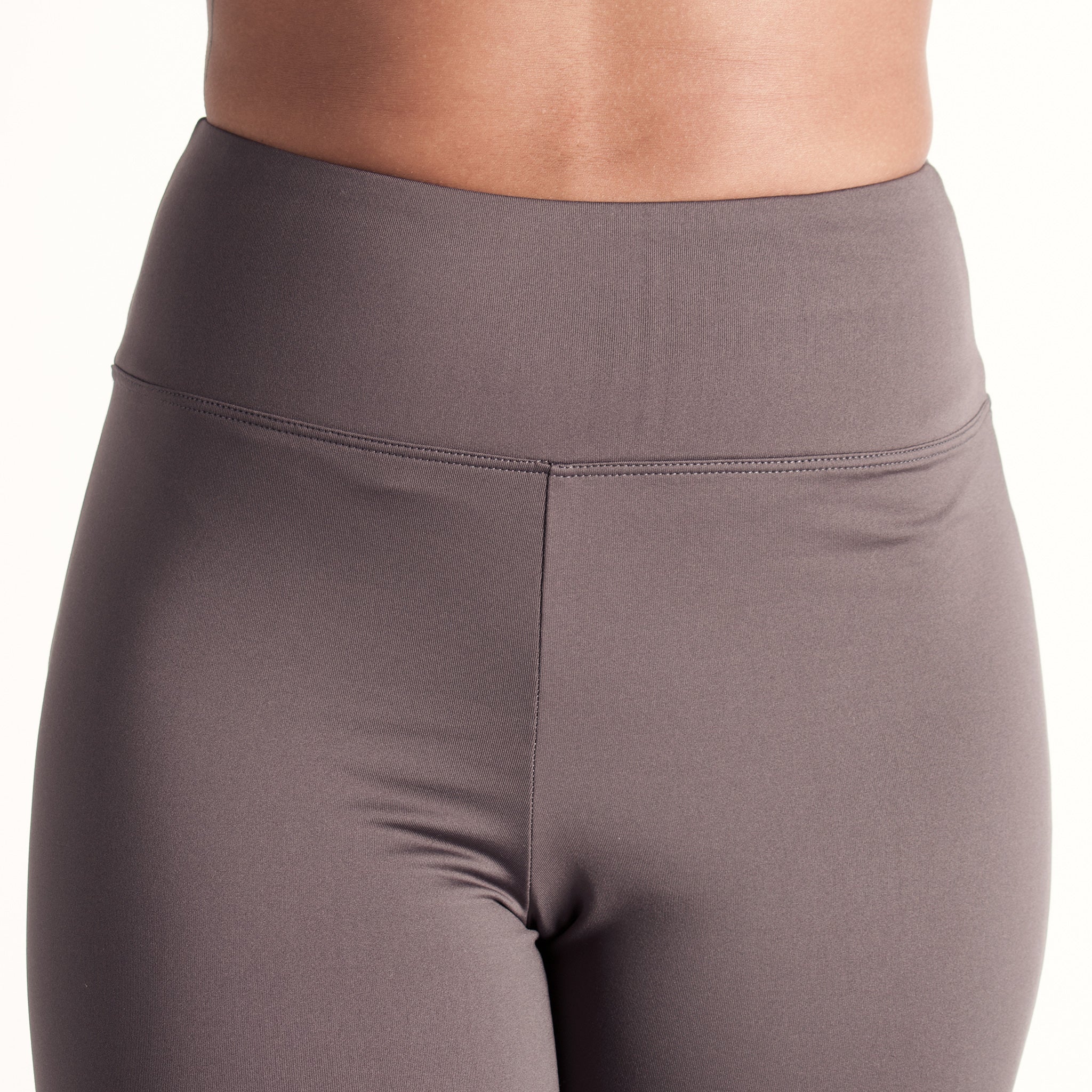 Woman wearing fitted light brown high-rise waist with ankle length leggings featuring seamless stitching and a hidden back pocket 