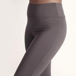 Woman wearing fitted light brown high-rise waist with ankle length leggings featuring seamless stitching and a hidden back pocket 