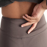 Woman wearing fitted light brown high-rise waist with ankle length leggings featuring seamless stitching and a hidden back pocket 