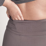 Woman wearing fitted light brown high-rise waist with ankle length leggings featuring seamless stitching and a hidden back pocket 